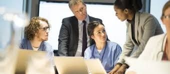 Business meeting in a conference room with people looking at laptops.