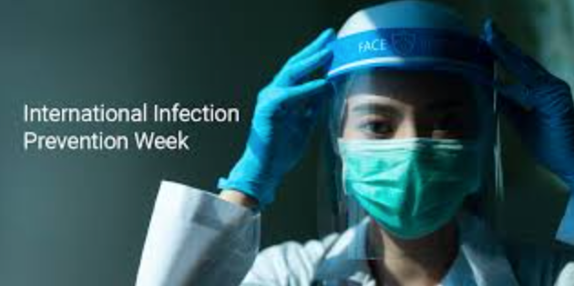 A doctor wearing a mask and a face shield is preparing for international infection prevention week.