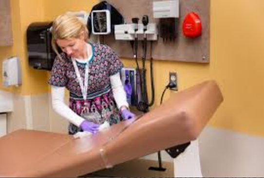 A nurse is cleaning a medical bed in a hospital room.