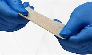 A person wearing blue gloves is stretching a piece of fabric.