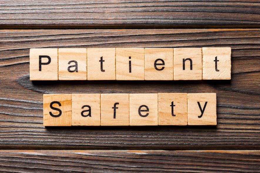 The word patient safety is written in wooden blocks on a wooden table.