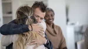 A man and a woman are hugging each other in a living room.