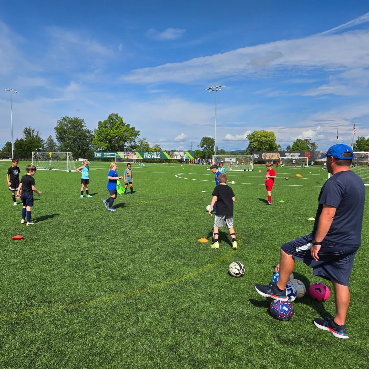 Two children playing soccer on a grassy field, one in navy and red, the other in white and blue