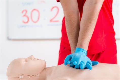 CPR training mannequin with gloved hands pressing on the chest