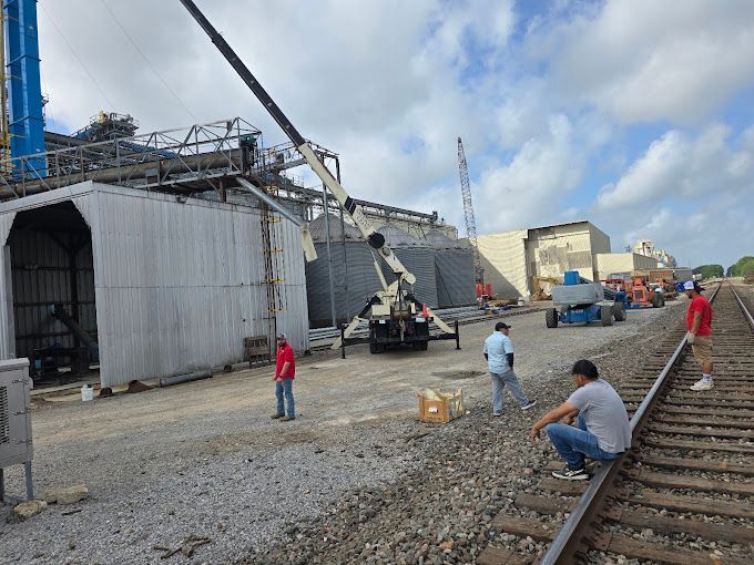 A group of men are sitting on train tracks in front of a building under construction.