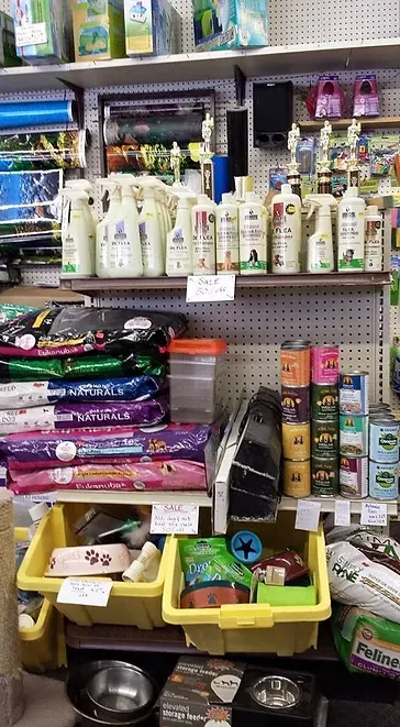 Shelves stocked with pet supplies including food, cleaning products, and toys in a pet store.