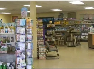 Pet supply store interior, shelves stocked with various pet products, a freestanding card display and a column.