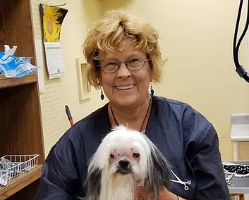Patty — Madison, WI — Noah's Ark Pet Center Woman in blue grooming smock holds a Shih Tzu dog, both smiling. Interior setting.
