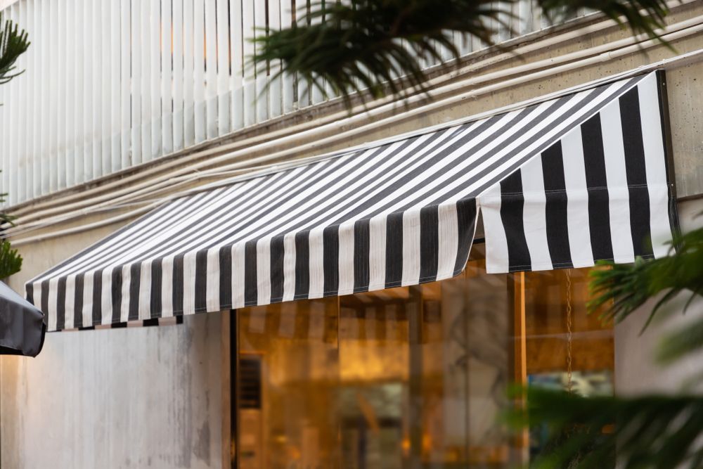Black-and-white Striped Awning Over a Storefront Entrance With Warm-lit Windows — Another Blind Man in Caloundra, QLD