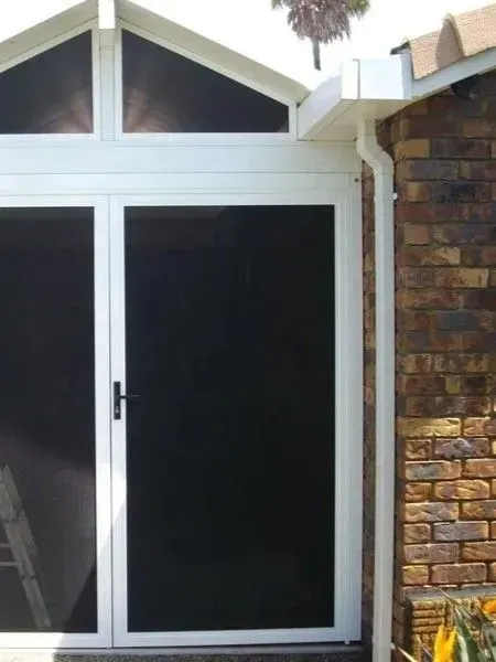 White-framed Sliding Glass Door Beside a Brick Wall and Triangular Window Panels Above — Another Blind Man in Tewantin, QLD