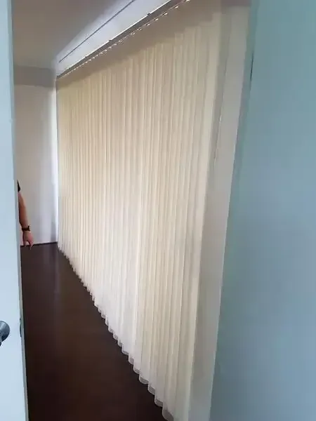 Closed Beige Vertical Blinds Lining a Hallway Beside a Dark Floor and White Wall — Another Blind Man in Tewantin, QLD