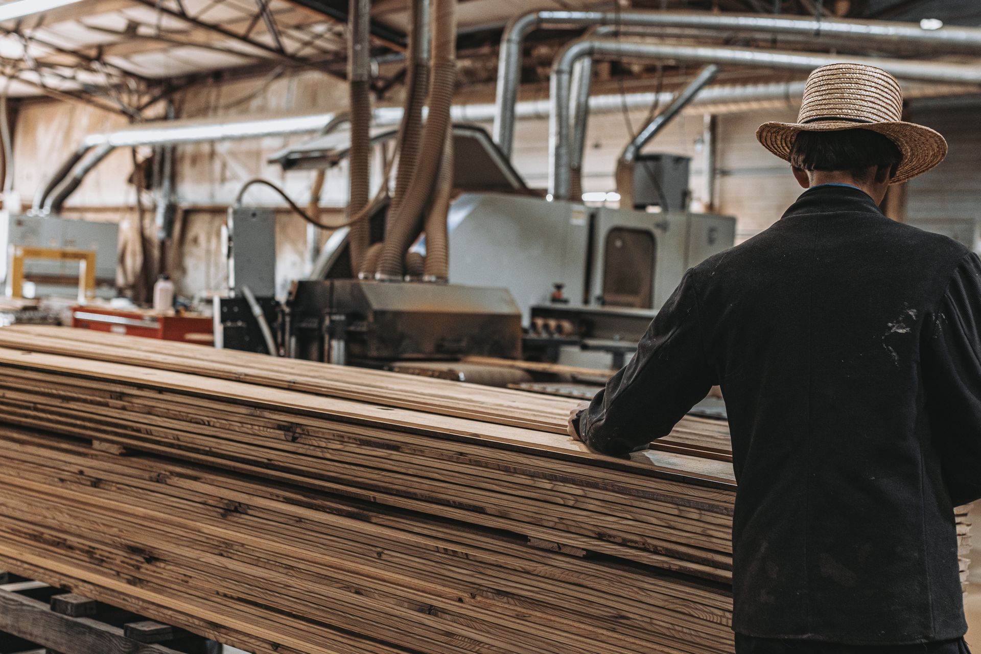 Worker inspecting recycled timber planks in a woodworking factory.