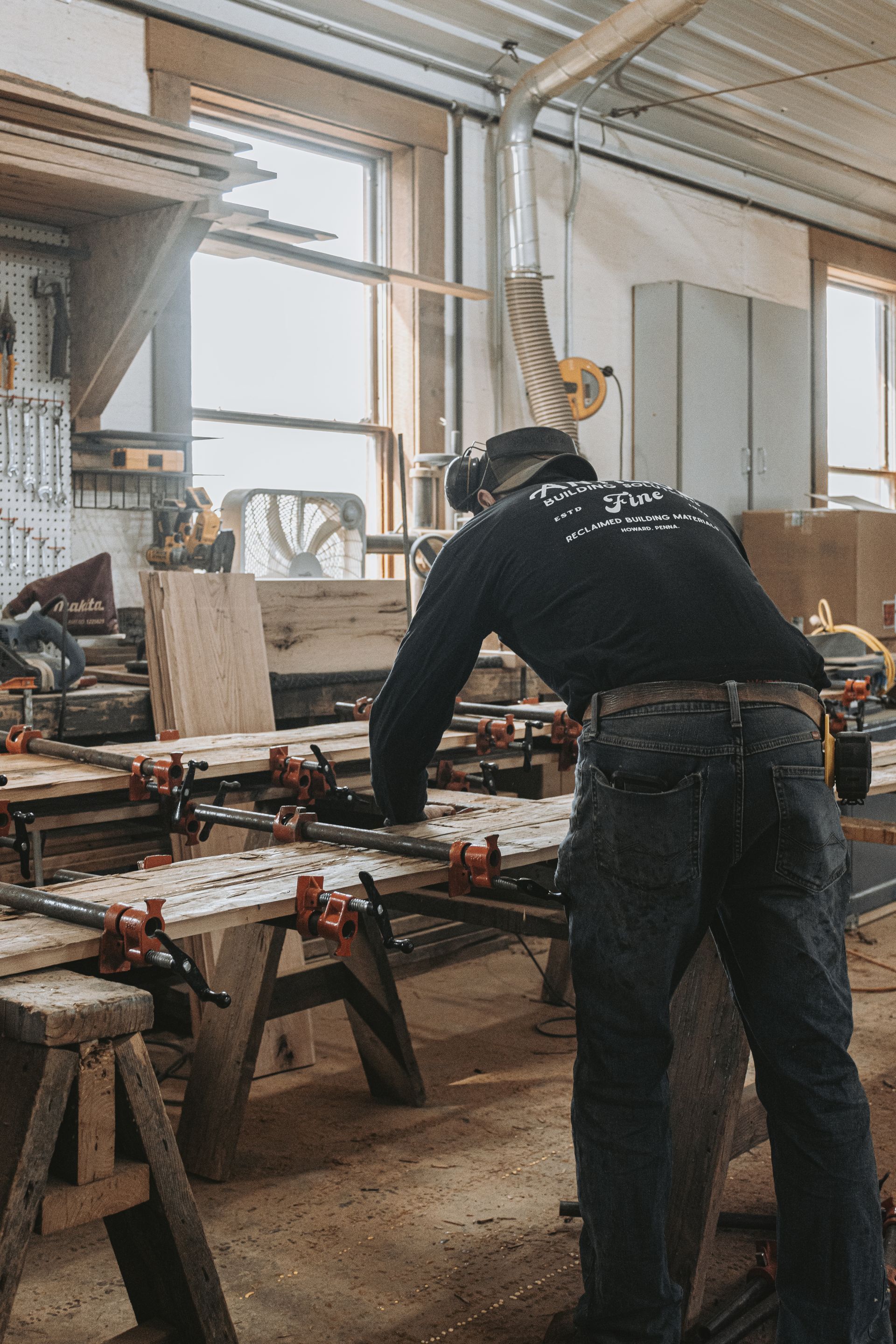 A craftsman clamps wooden planks together on a workbench, reflecting ancient woodworking techniques.