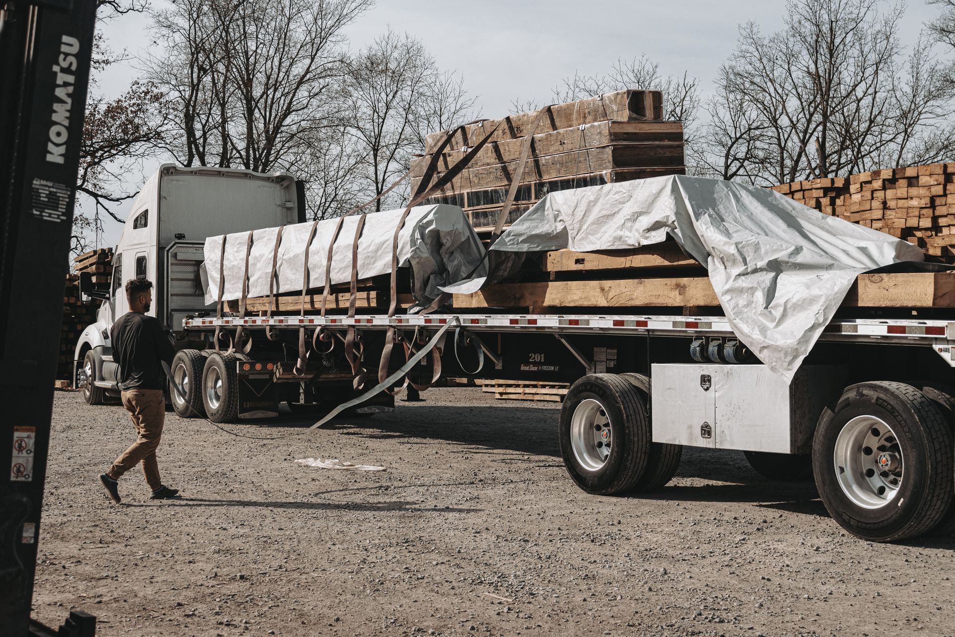 Flatbed truck loaded with timber in a lumberyard, part of reclaimed antique wood suppliers operations.