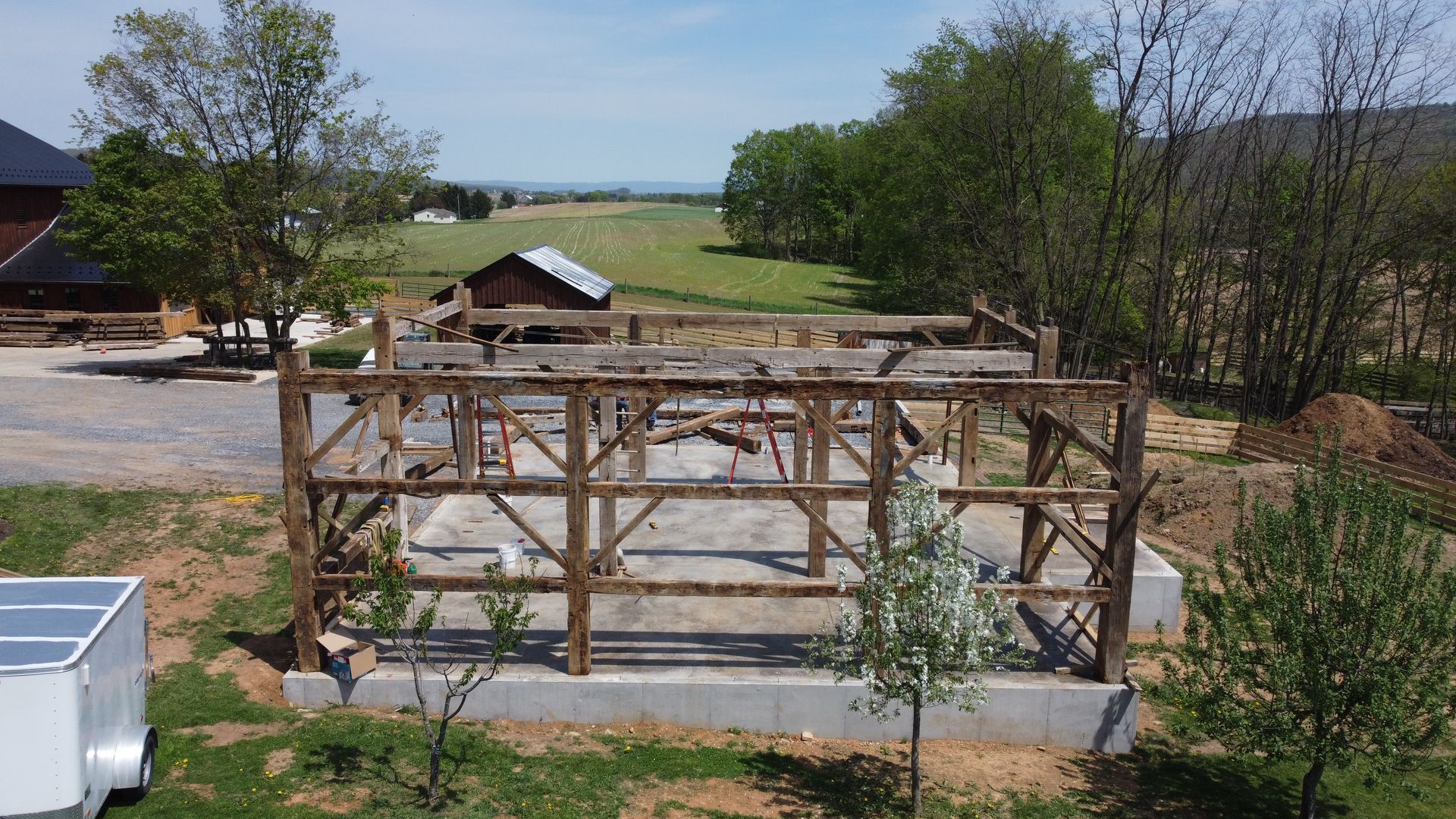 Timber frame on concrete foundation in rural setting, showcasing restored barns.