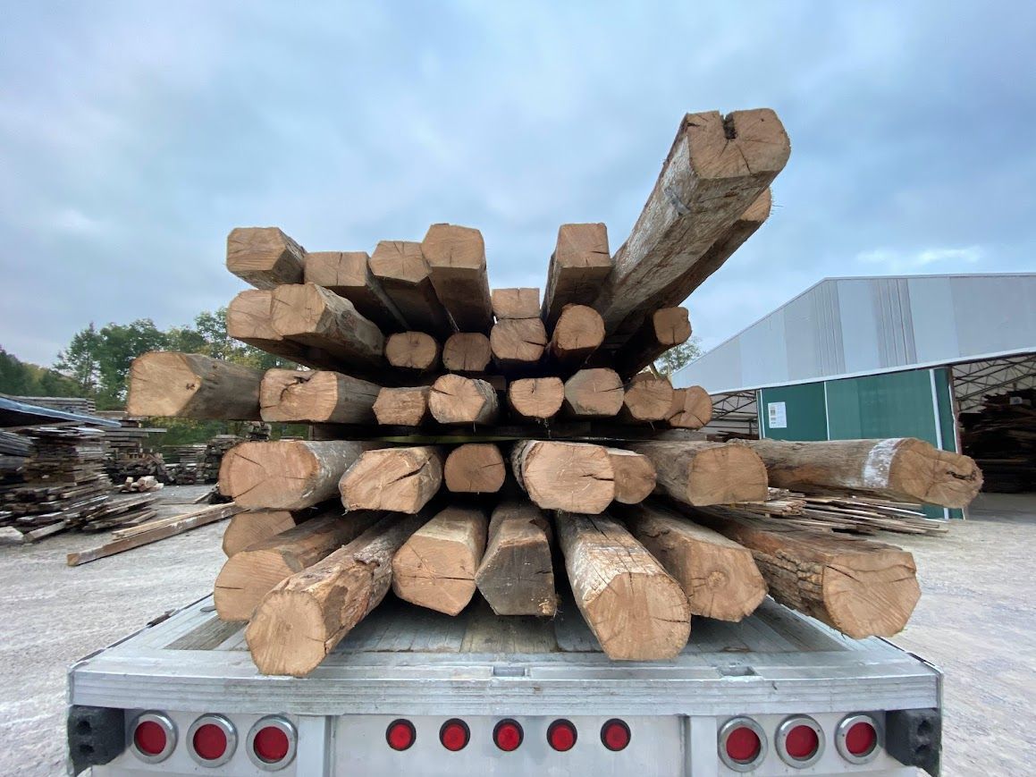 Stacked aged beams on truck showing wood shrinkage.