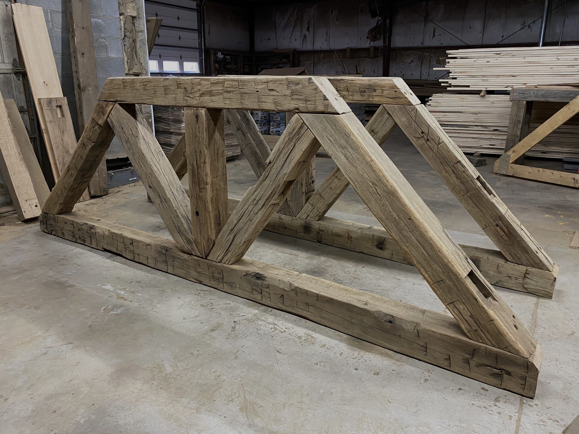 Reclaimed hand-hewn girder truss ready for assembly in a Pennsylvania timber framing shop.
