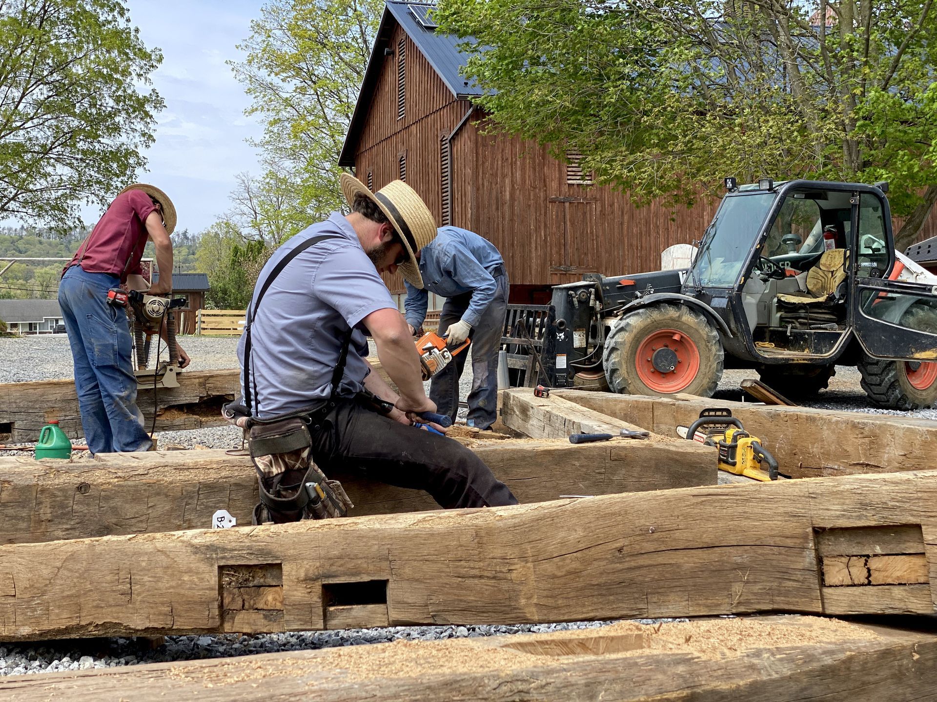 Craftsmen restoring timber beams beside a rustic barn, showcasing wedding barn conversions with authentic, hand-built details.