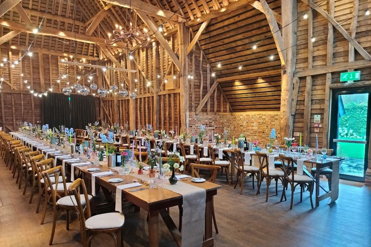 Rustic barn interior with long tables, floral decor, and string lights, perfect to rent a barn for a party or celebration.