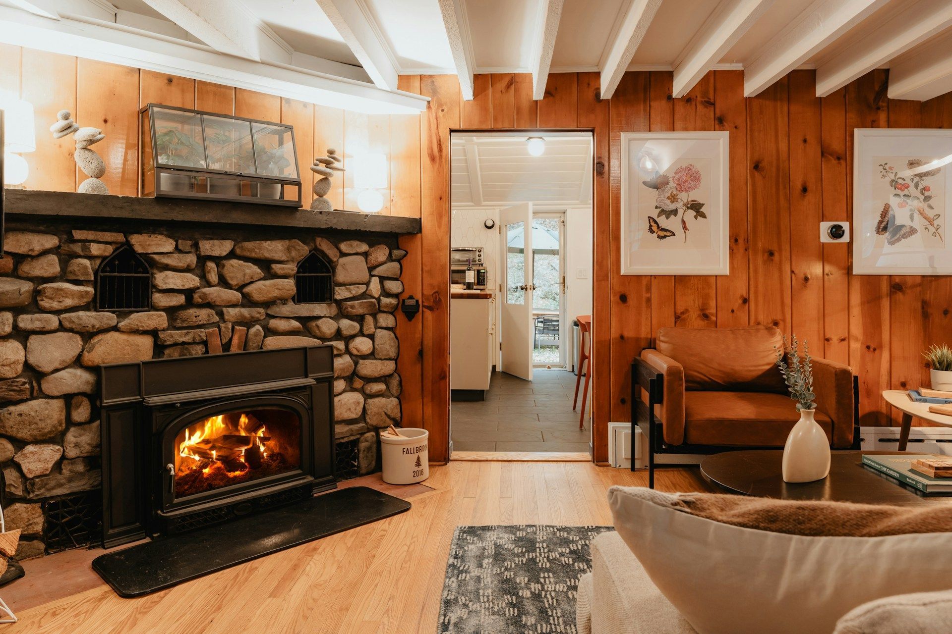 American barndominium living room with a stone fireplace and timber beams.