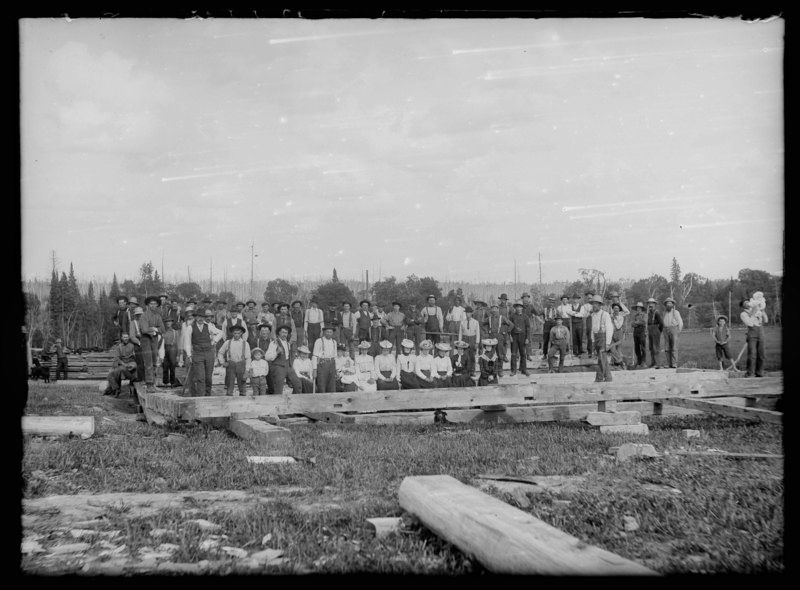 Public-domain,-via-Wikimedia-Commons A black and white photo of a group of people standing in a field.