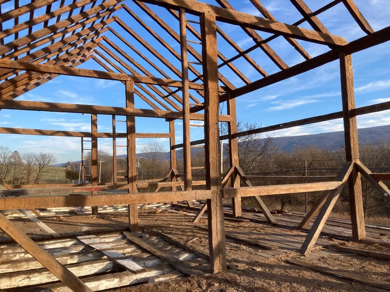 Raw timber frame house plans with exposed beams and rafters under the open sky in America.
