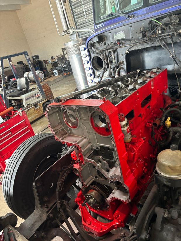 A bright red, partially disassembled heavy-duty truck engine sits exposed in a workshop.