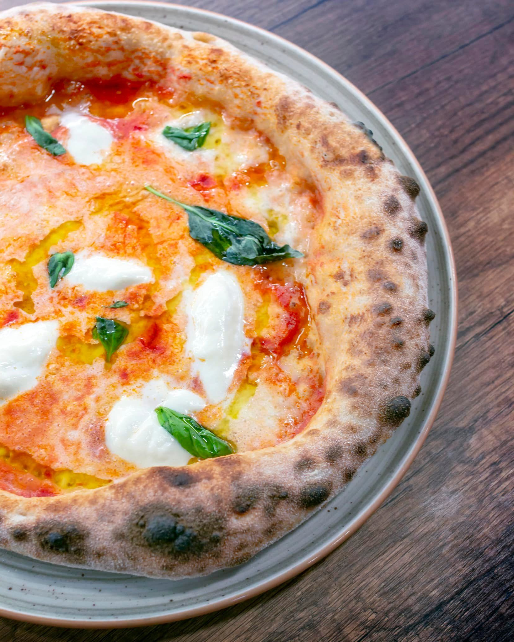 Pizza napoletana margherita su un piatto grigio.