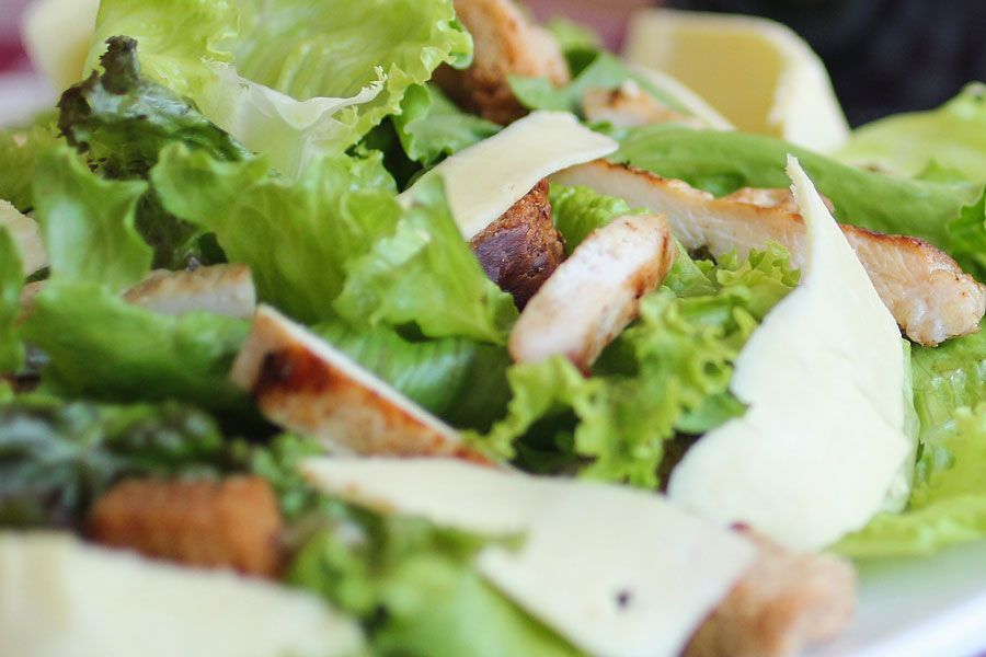 Insalata di lattuga con pollo grigliato a fette e formaggio.