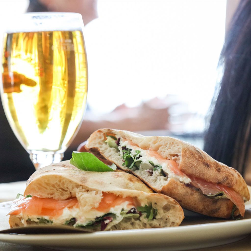 Panuozzo con salmone su un piatto, con un bicchiere di birra sullo sfondo.