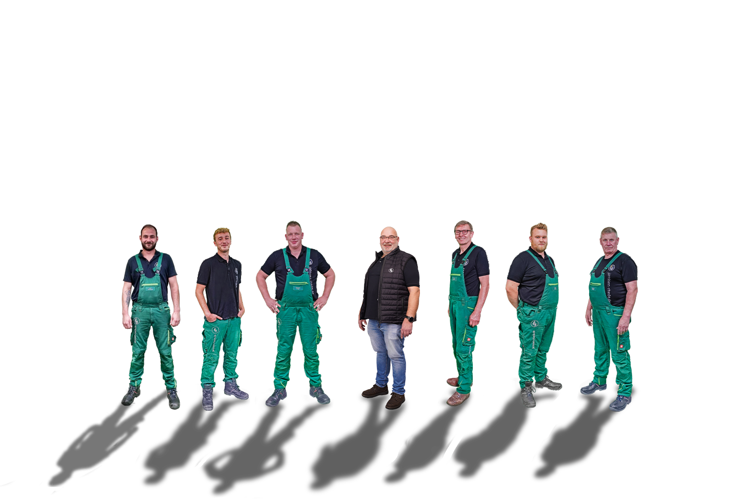 Sieben Fachkräfte stehen in einer Reihe vor einem weißen Hintergrund und tragen einheitliche grüne Arbeitsoveralls und schwarze Hemden.