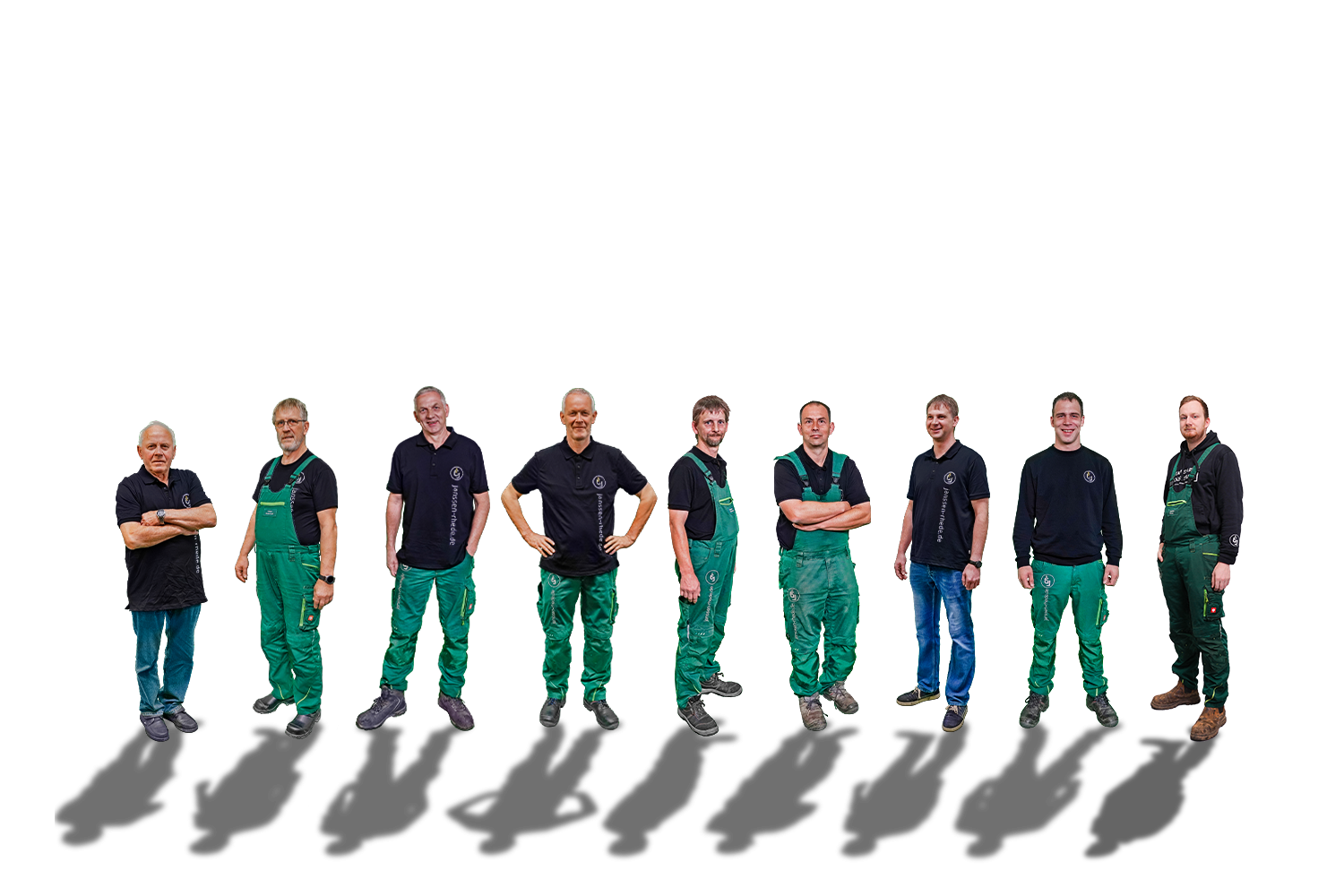 Neun Personen stehen in einer Reihe vor einem weißen Hintergrund und tragen Arbeitskleidung, meist grüne Overalls oder schwarze Hemden.