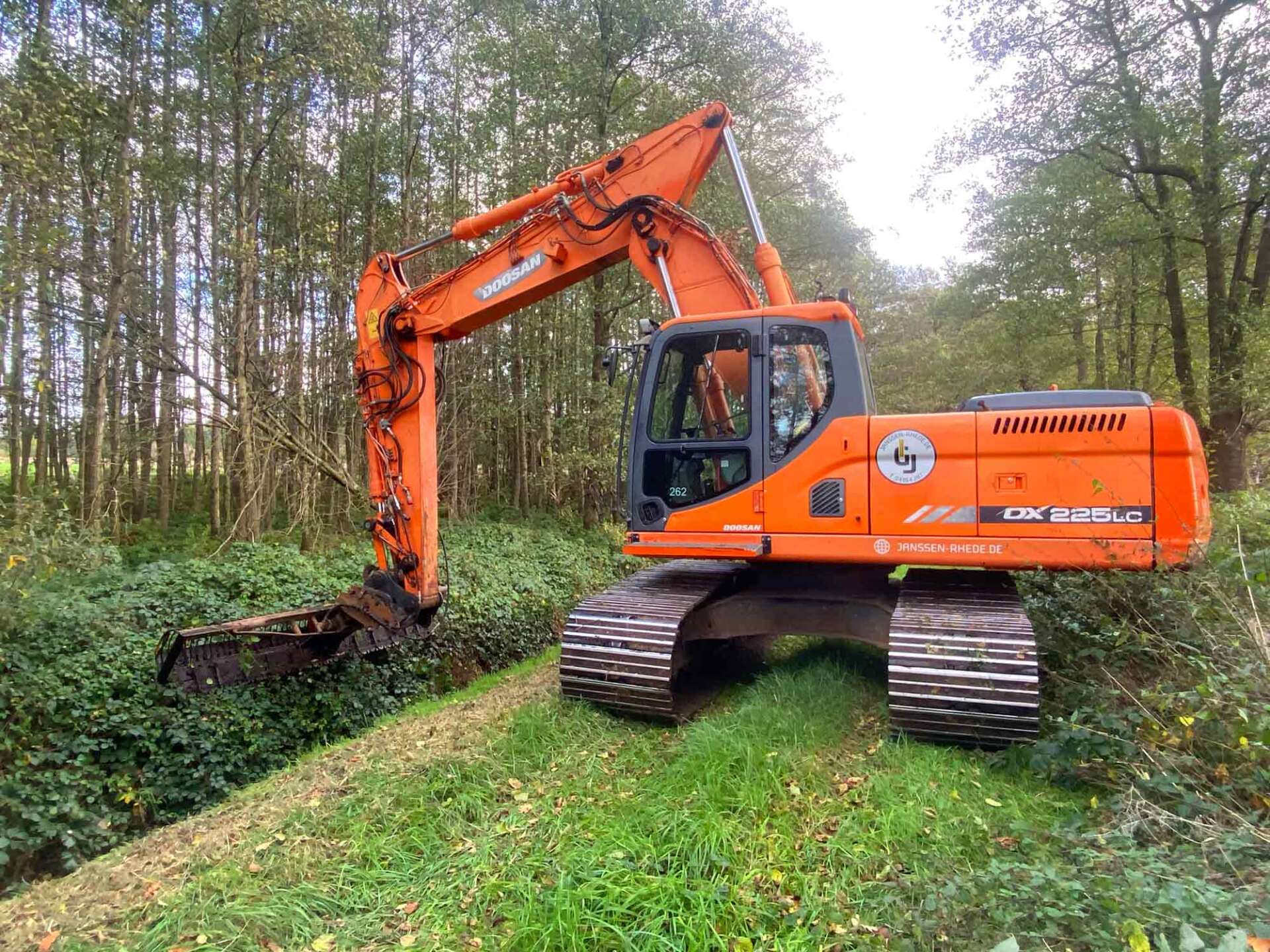 Ein großer orangefarbener Bagger steht auf einem grünen Feld.