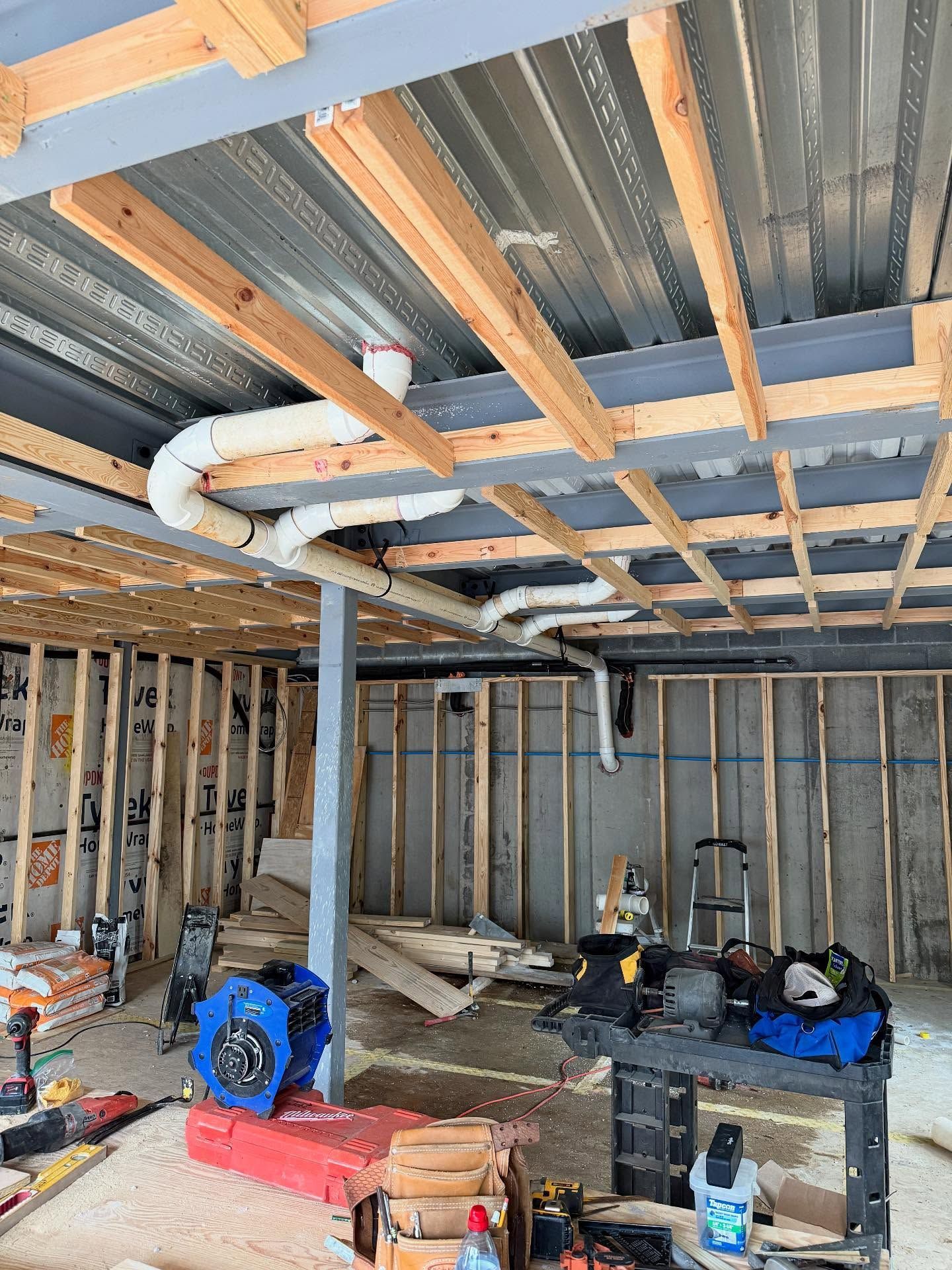 Unfinished room with exposed studs, insulated ceiling, construction tools, and materials on the floor