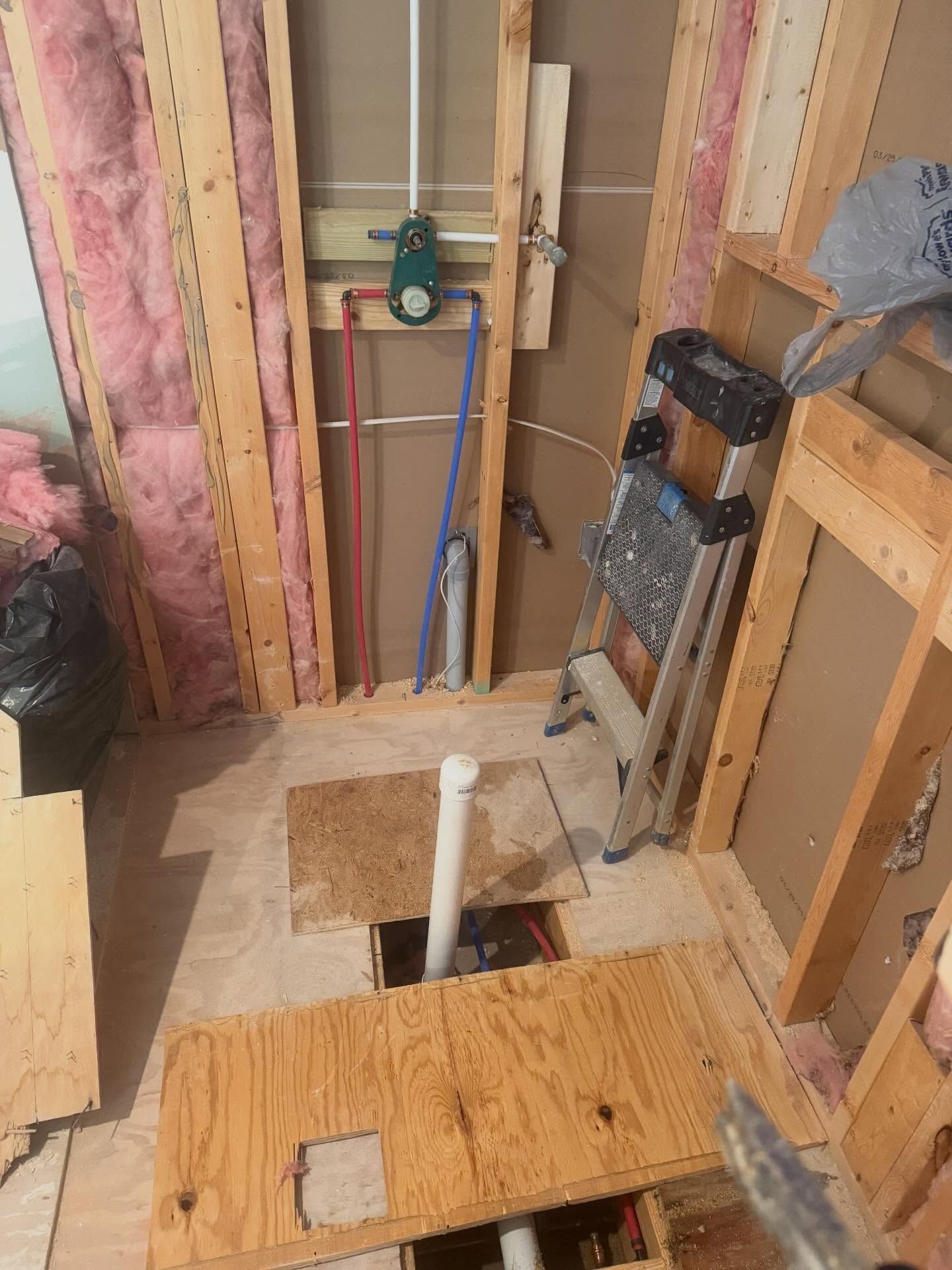 Partially framed bathroom floor with an open toilet drain and exposed plumbing under construction