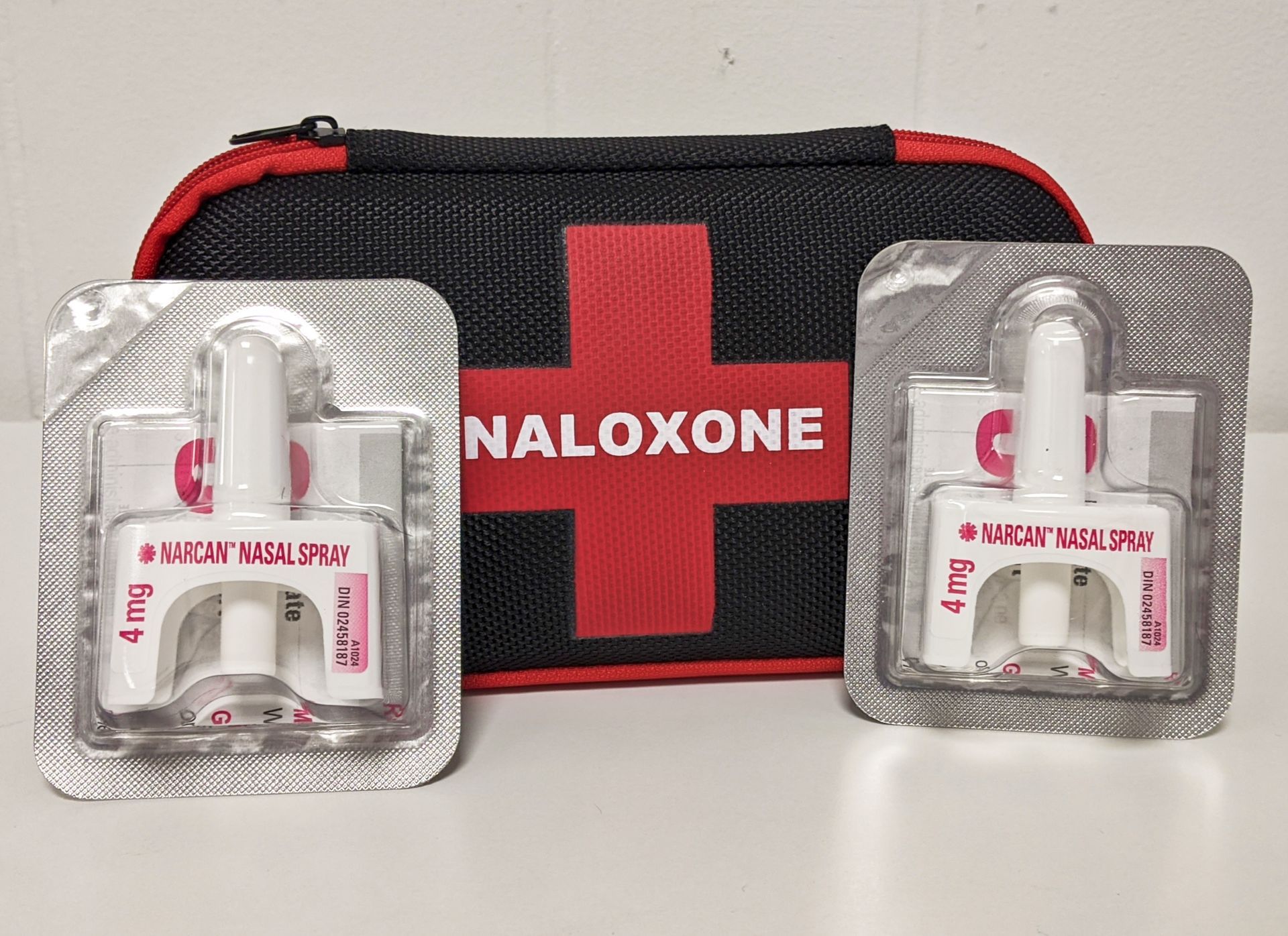 Two blister packs of naloxone next to a first aid kit