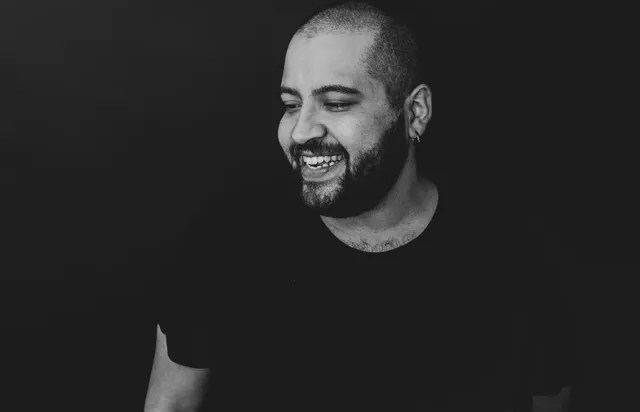 A man with a beard is smiling in a black and white photo.