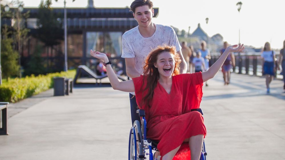 A Happy Young Woman In A Red Dress Is In A Wheelchair — Comfort N Care Support QLD Pty Ltd In Roma, QLD
