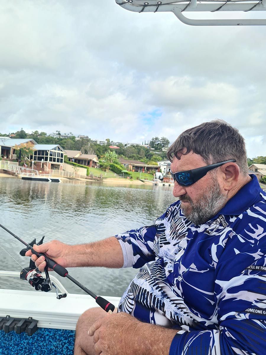 A Man Is Sitting on A Boat Holding a Fishing Rod — Comfort N Care Support QLD Pty Ltd In Toowoomba City, QLD
