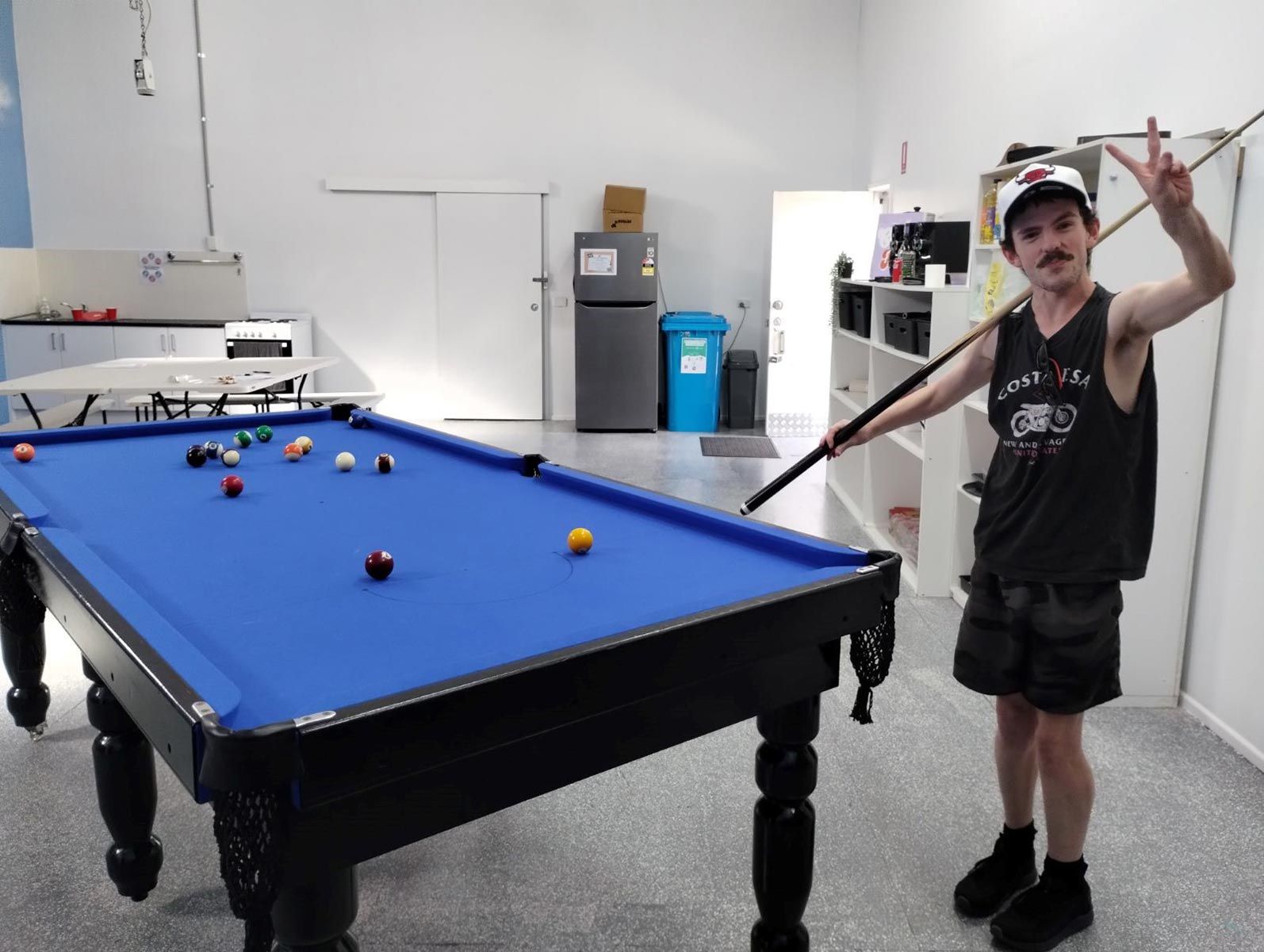 A Man Is Holding a Pool Cue in Front of A Pool Table — Comfort N Care Support QLD Pty Ltd In Toowoomba City, QLD