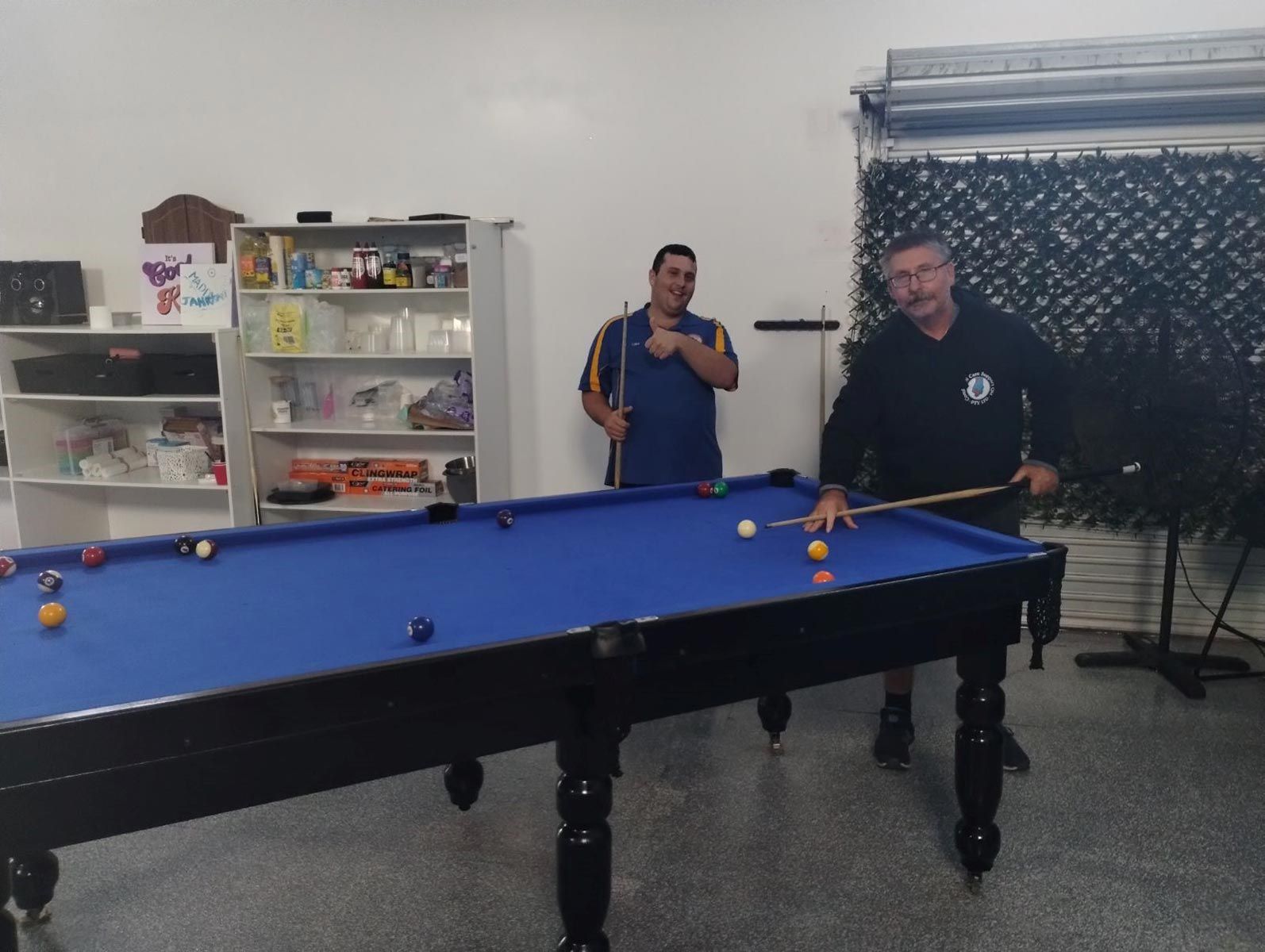 Two Men Are Playing Pool in A Room with A Pool Table — Comfort N Care Support QLD Pty Ltd In Toowoomba City, QLD