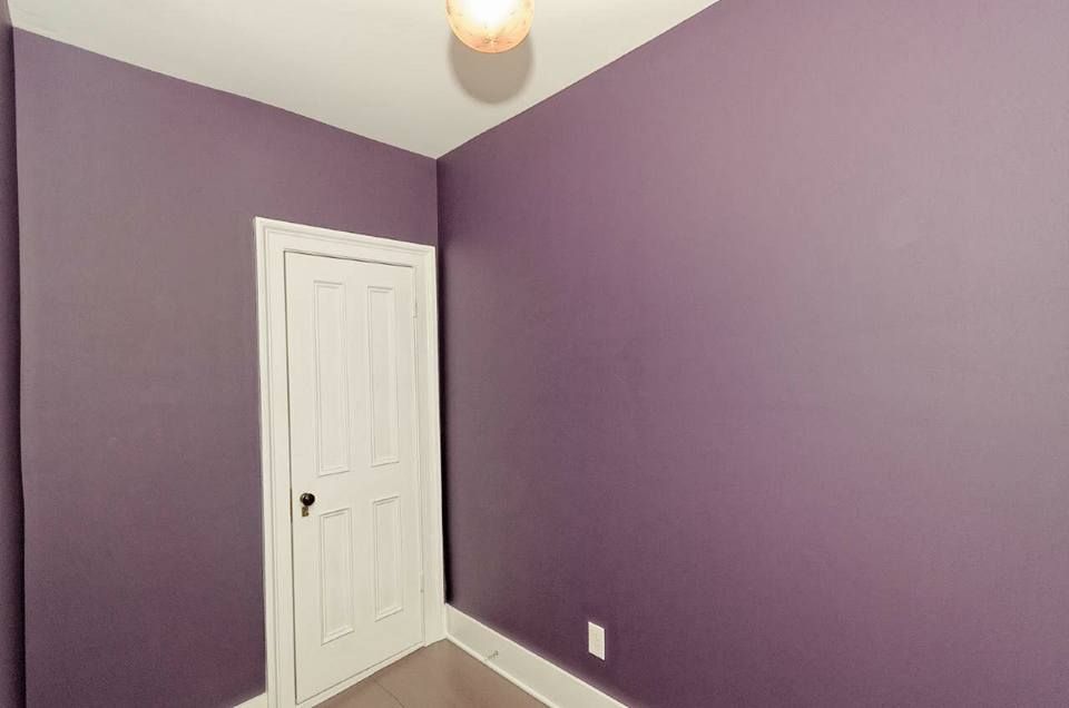 A room with purple walls and a white door.