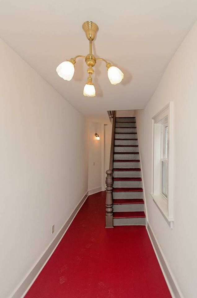 A hallway with stairs and a red carpet
