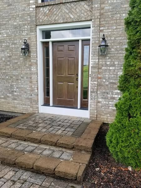A brick house with a wooden front door and steps leading to it.