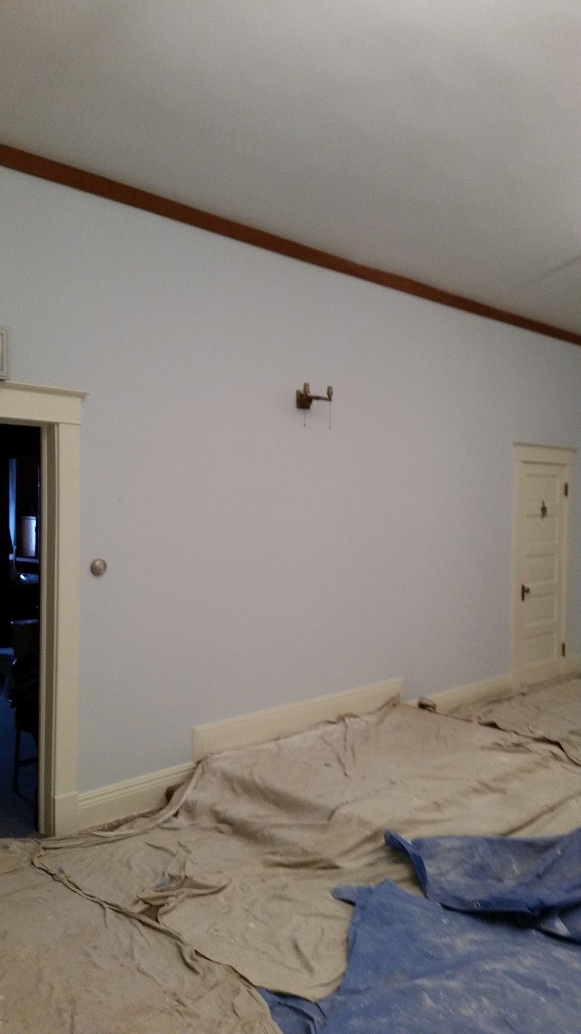 A room with white walls and a blue tarp on the floor.