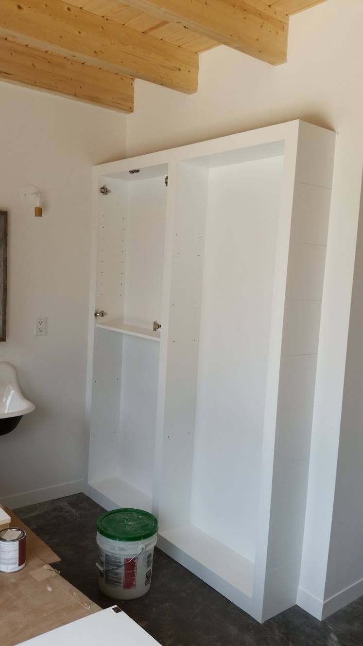 A white cabinet with a green bucket next to it in a room.