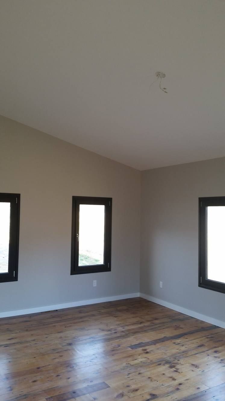 An empty room with hardwood floors and three windows.