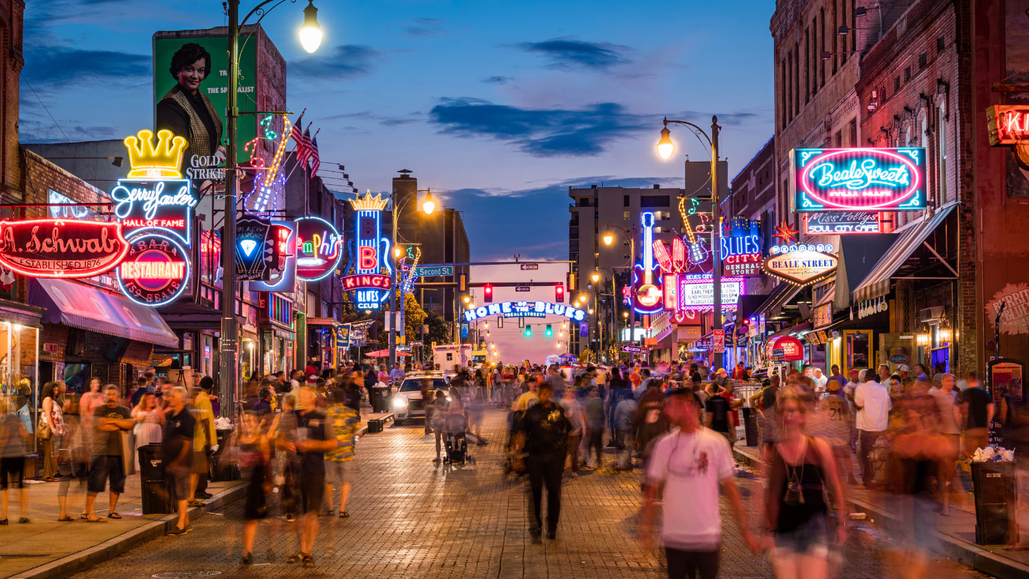 Crowded neon-lit street at dusk with pedestrians and colorful signs lining both sides
