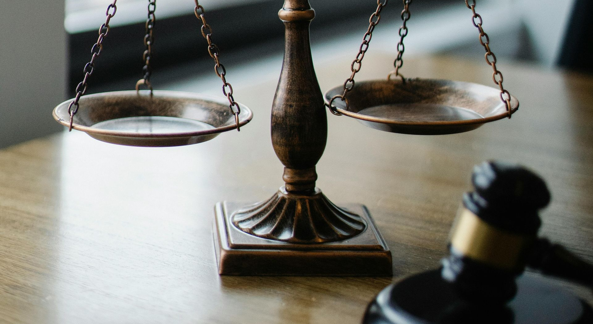 Law scales and a gavel on a desk, symbolizing justice and legal proceedings
