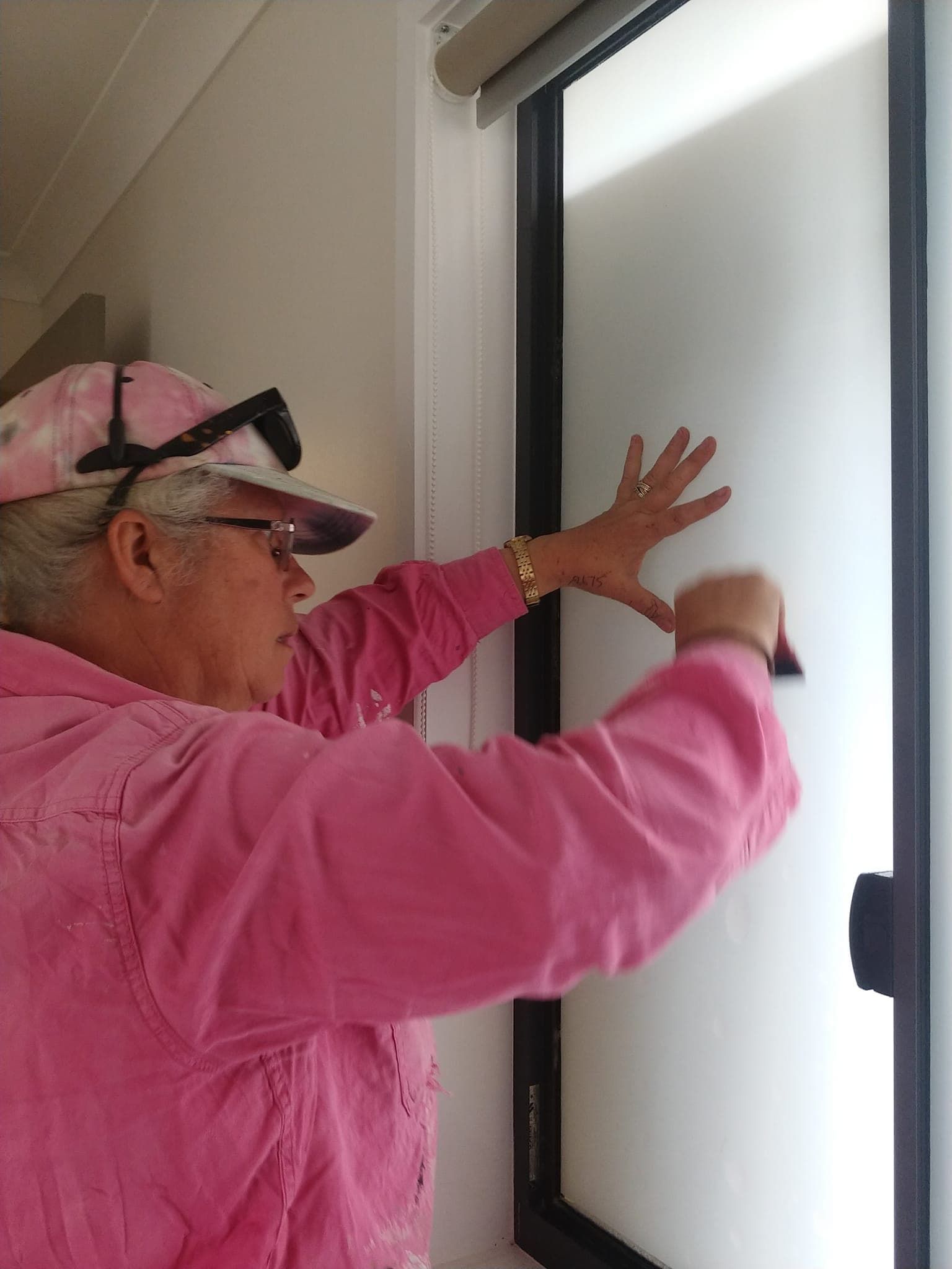 A Woman in A Pink Jacket and Hat Is Reaching for A Window — Your Local Handywoman in Burnett Heads, QLD